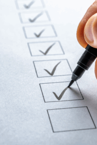 A hand marking a checklist with a black pen — a concept for a trustworthy website check to ensure quality and credibility factors are met.