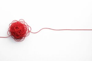 Red thread tangled, then straight, symbolizing clear and concise business communication examples.